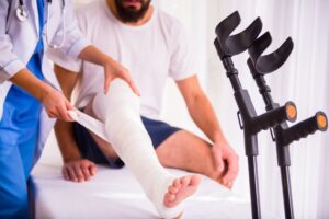 Young man with an injured leg receives help from a female doctor.