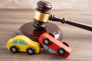 Judge's gavel with a car symbolizes a vehicle accident, insurance coverage claim, and lawsuit court case.