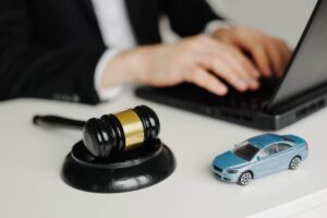 Car accident liability insurance lawyer with a gavel, using a laptop.