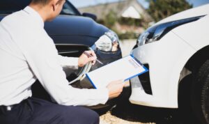 Insurance agents inspect car collision damage on the road to process compensation claims for driving accidents, emphasizing the importance of insurance coverage.