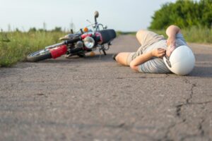 A man lies on the asphalt near his motorcycle, highlighting the theme of road accidents.






