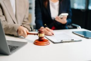 Business lawyers consult with women entrepreneurs on filing copyright lawsuits, using a laptop and tablet in the office. Business law concept.